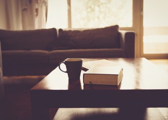 Salon avec canapé au fod une table en bois avec un café et un livre