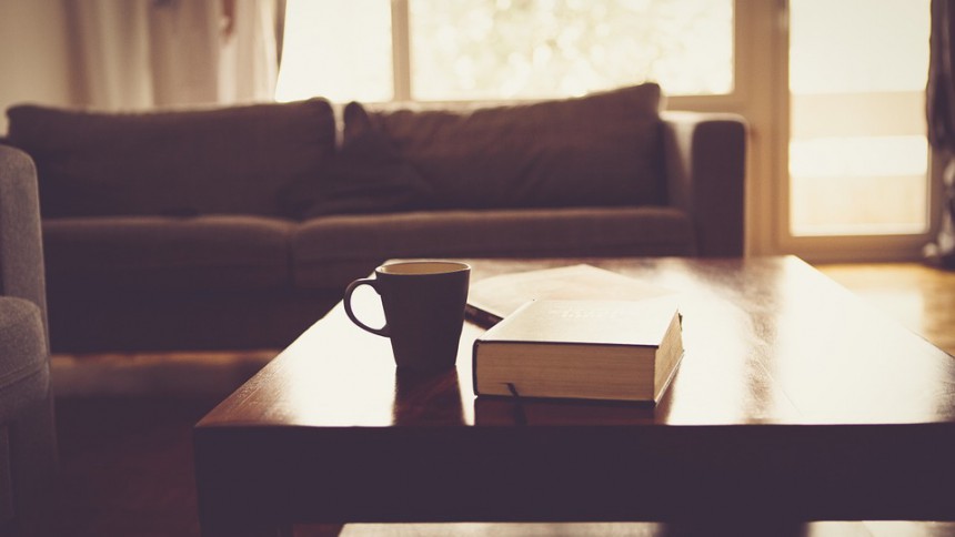 Salon avec canapé au fod une table en bois avec un café et un livre